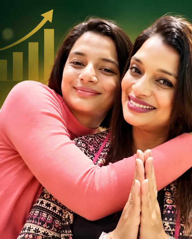 Amarja Nafrey smiling with her hands joined as a young woman hugs her from behind